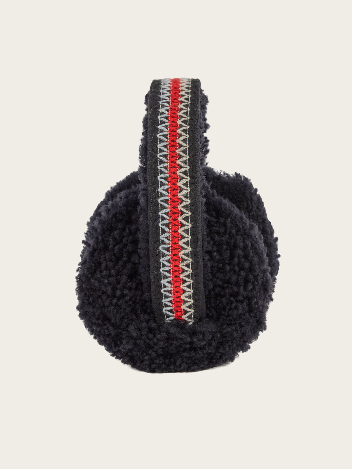 The EMU x WN Angahook Teddy Earmuff by We Norwegians showcases black fuzzy earmuffs with a teddy finish and textured surface, made from plush Merino wool. The headband is highlighted by a central red stripe bordered by white zigzag patterns, and the earmuffs are presented against a plain white background.