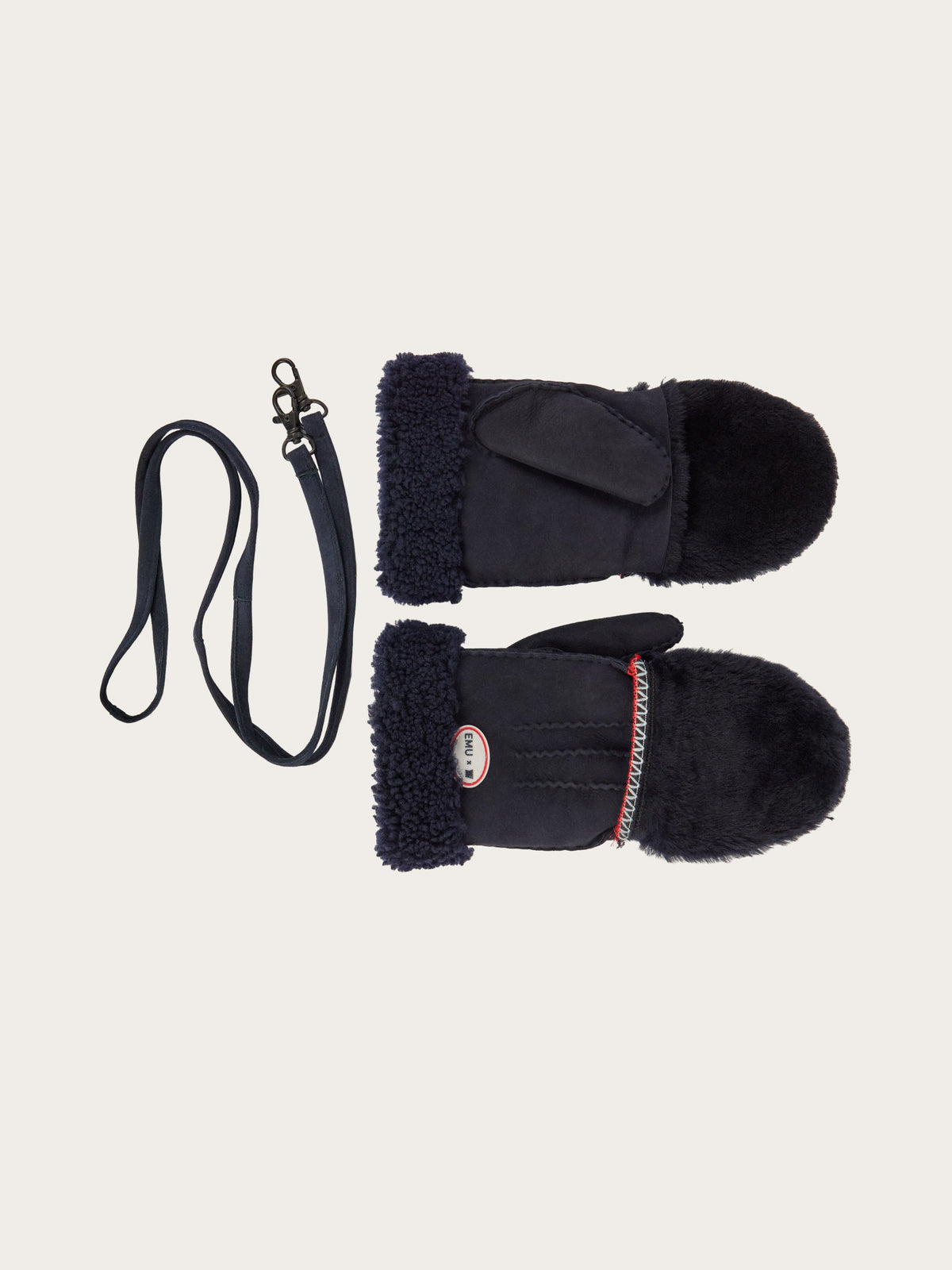 The EMU x WN Montana Mittens by We Norwegians are black sheepskin mittens featuring a fuzzy cuff and a red accent, displayed alongside a coordinating black strap with a metal clasp—ideal cold-weather accessories for alpine living.
