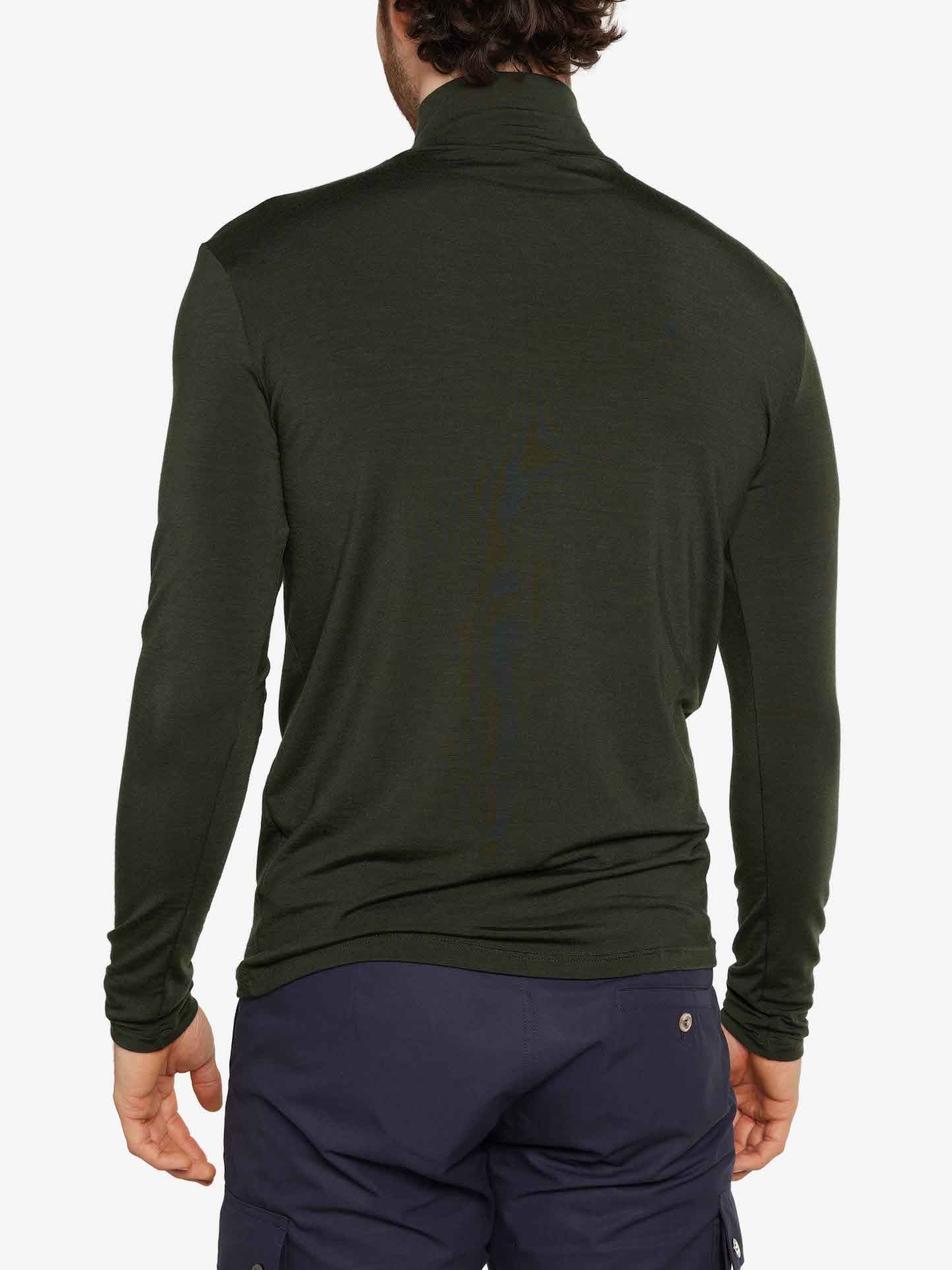A person is seen from the back wearing the Hygge Zip Up Men Olive Green by We Norwegians, paired with dark blue pants that feature pockets. Both items are crafted from soft Merino wool against a plain white background.